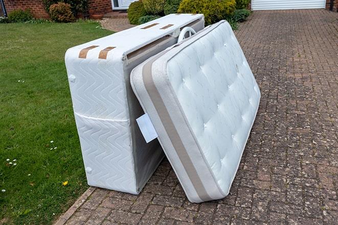 two workers lifting a mattress into a removal truck